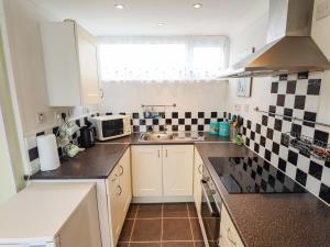 a kitchen with white cabinets and black and white tiles at Seaside Retreat in Skegness