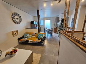 ein Wohnzimmer mit einem Sofa und einer Uhr an der Wand in der Unterkunft O villa* Studio avec clim et calme *Wifi* in Villasavary
