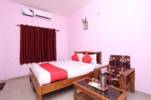 a bedroom with a bed and a table with a chair at OYO Sambit Nx in Bhubaneshwar