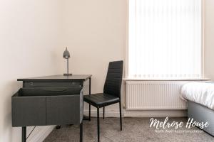 ein Schlafzimmer mit einem Schreibtisch und einem Stuhl neben einem Bett in der Unterkunft Melrose Contractor Accommodation in Manchester
