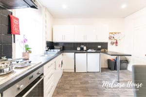 a kitchen with white cabinets and a black counter top at Melrose Contractor Accommodation in Manchester