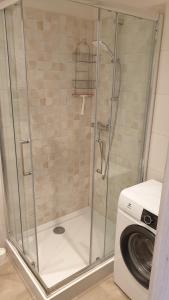 ducha con puerta de cristal junto a una lavadora en Apartament Malinka, en Opole 2 fotos más