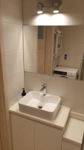 Un baño con un lavabo blanco y un espejo. en Apartament Malinka, en Opole