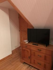 a flat screen tv sitting on top of a wooden dresser at La Longre in Cerisy-la-Forêt