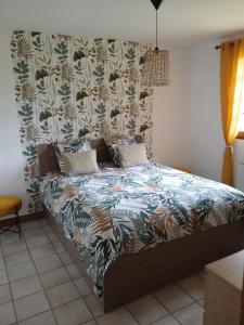 1 dormitorio con 1 cama con colcha de flores en Gite meublé avec étang en lisière de forêt., en Les Grandes Prouillères