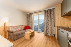 a living room with a couch and a large window at Berghotel Jaga-Alm in Zell am See