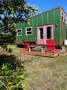 een groen tiny house met rode stoelen in een tuin bij Evergreen in Waldport