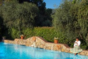 a woman sitting on a stone wall next to a swimming pool at Locanda Del Molino in Cortona