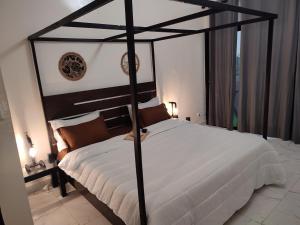 um quarto com uma cama de dossel preta com lençóis brancos em La residence latinaya em Poponguine