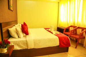 Schlafzimmer mit einem Bett mit roten und weißen Kissen in der Unterkunft AKAN HOTEL AND RESIDENCE in Wayanad