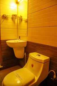 a bathroom with a yellow toilet and a sink at AKAN HOTEL AND RESIDENCE in Wayanad