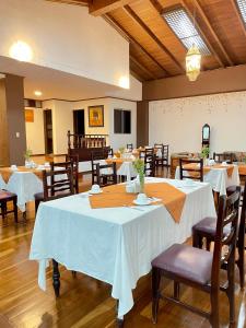 a dining room with tables and chairs with white tablecloths at Loft NASS Atahualpa in Cuenca