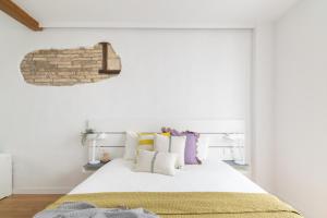 a bedroom with a white bed with colorful pillows at Increíble, amplio, cómodo y céntrico apartamento in Pamplona