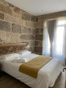 Arbo的住宿－Reginita Apartamentos，一间卧室设有一张带石墙的大床
