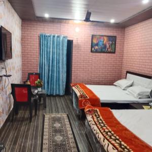 a bedroom with two beds and a tv in it at Somnath residency radhe nikunj in Vrindāvan