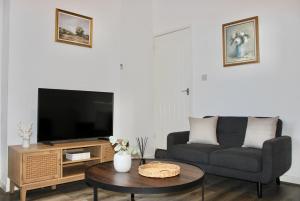 a living room with a couch and a tv at Chic & Cushy 3 Bed House, short and long term in Birmingham