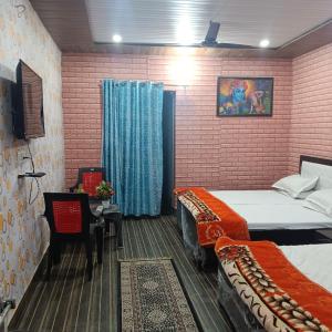 a bedroom with two beds and a table with a chair at Somnath residency radhe nikunj in Vrindāvan