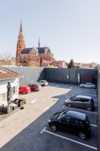 un estacionamiento con autos estacionados frente a un edificio en Pansion Strossmayer en Osijek