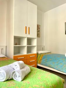 a bedroom with two beds and a dresser with towels at Sea la Vie in Alghero