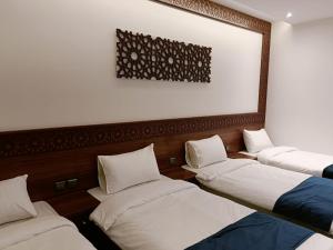 a room with three beds and a picture on the wall at فندق نجمة العزيزية Star AL Aziziyah in Makkah