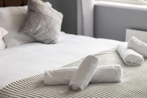 Una cama blanca con toallas y almohadas. en The Kilnwood House, en Crawley