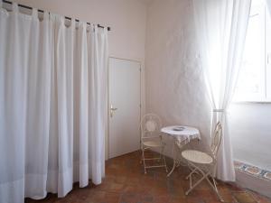 セッサ・アウルンカにあるPonteronico Resortの白いカーテン、テーブルと椅子が備わる客室です。