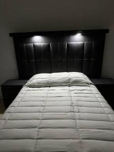 a white bed with a black headboard in a bedroom at Hermoso Descanso en Coyoacán in Mexico City
