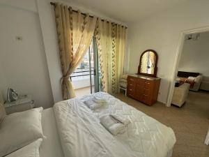 1 dormitorio con 1 cama con sábanas blancas y ventana en Taulant, en Sarandë