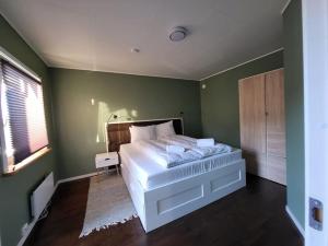 a bedroom with a large bed and a green wall at Sweet Cabin Leknes in Leknes