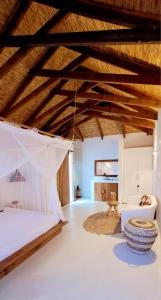 1 dormitorio con cama, sofá y techos de madera en Karula Sand Villas - Coral Villa - Barra Beach, Inhambane, Mozambique, en Inhambane