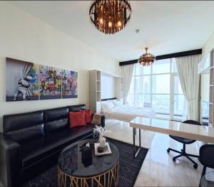 uma sala de estar com um sofá, uma mesa e uma cama em Beautiful Studio Apartment in Bayz Tower - near Downtown Area em Dubai