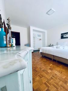 una camera bianca con letto e pavimento in legno di Itaca Experience Playa do Cabedelo a Viana do Castelo