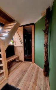 Habitación con paredes verdes, suelo de madera y escalera. en Gastenhuisje en Zelhem