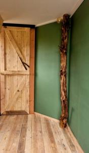 una habitación con una pared verde, una puerta y un árbol en Gastenhuisje en Zelhem
