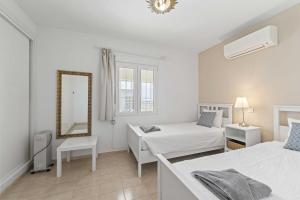 Habitación blanca con 2 camas y espejo. en 1100 Marbella Beachfront first line en Marbella
