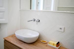 La salle de bains est pourvue d'un lavabo blanc sur un comptoir en bois. dans l'établissement Michelangelo Luxury Apartment, à Florence