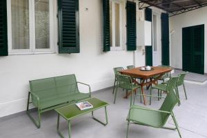 d'une terrasse avec des chaises vertes, une table et des chaises en bois. dans l'établissement Michelangelo Luxury Apartment, à Florence