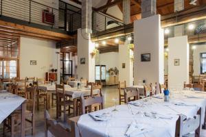 ein Esszimmer mit weißen Tischen und Holzstühlen in der Unterkunft Ostello IMPERINA in Zenich
