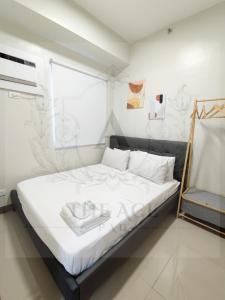 una camera da letto con un letto con lenzuola bianche e una finestra di THE ACE PAD at SMDC Charm Residences a Manila