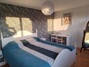 a bedroom with a bed with a blue and white comforter at La fleur du soleil in Trouville-sur-Mer