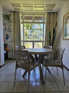 d'une salle à manger avec une table, des chaises et une fenêtre. dans l'établissement Descanso Aconchegante, à Maceió