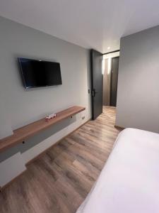 a bedroom with a bed and a tv on a wall at Aerosuites in Bogotá