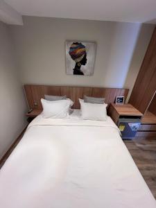 a bedroom with a large white bed with a wooden headboard at Aerosuites in Bogotá