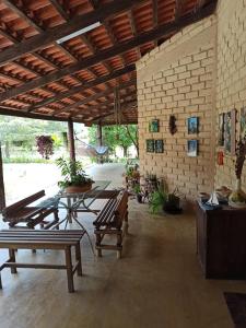 a patio with a table and benches and a brick wall at Chalés Pássaros do Cerrado in Cavalcante