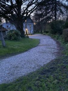 a gravel road with a tree and a building at Petit manoir de la berthenlaire in Baincthun