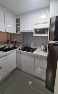 uma cozinha com armários brancos e electrodomésticos de aço inoxidável em Hermoso departamento en norte de Quito em Quito