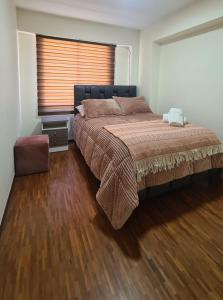 um quarto com uma cama grande e piso em madeira em Hermoso departamento en norte de Quito em Quito