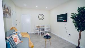 a living room with a couch and a clock on the wall at F3 Ground floor Luxury flat Gants Hill in Redbridge