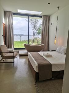 sypialnia z łóżkiem i krzesłem oraz dużym oknem w obiekcie Dzixile w mieście Gueima