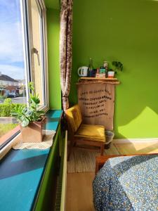 1 dormitorio con paredes verdes, silla y ventana en The Green Room Homestay, en Galway